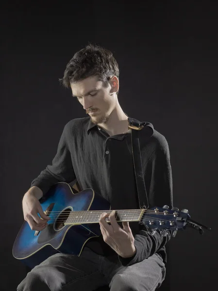 Um guitarrista masculino afinando a guitarra — Fotografia de Stock