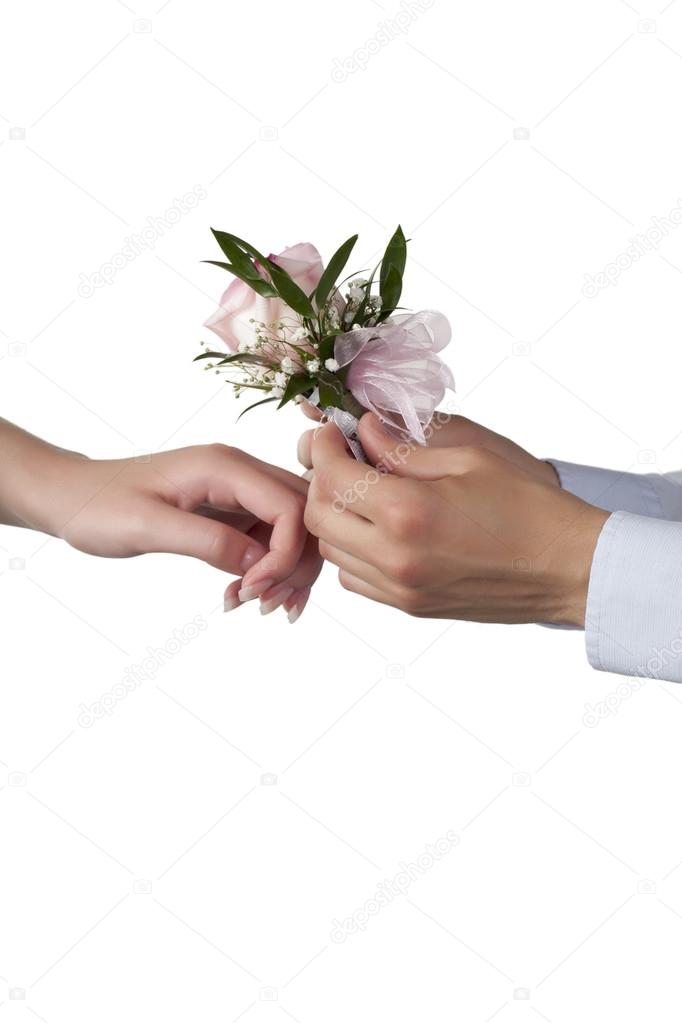 a guy putting a rose corsage on the womans wrist