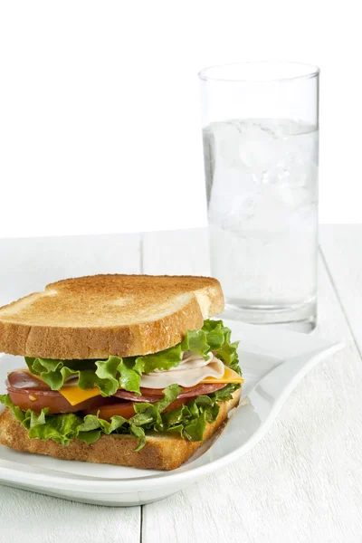 Un piatto con panino al prosciutto e un bicchiere d'acqua — Foto Stock