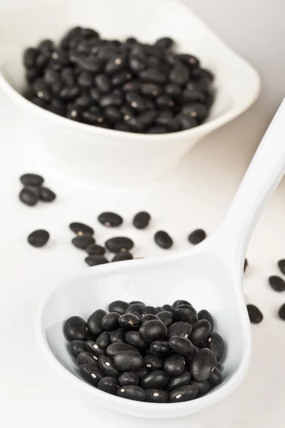 Una cucharada de frijoles negros en un tazón blanco — Foto de Stock