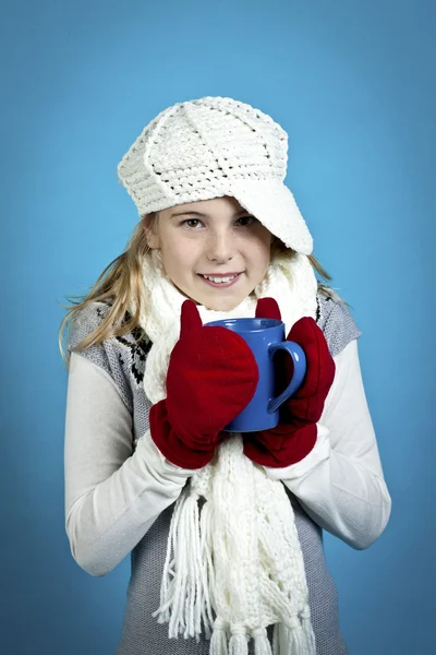 Une jeune fille qui boit du chocolat chaud sur fond bleu — Photo