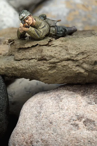 A sniper miniature lying on the rocks — Stock Photo, Image