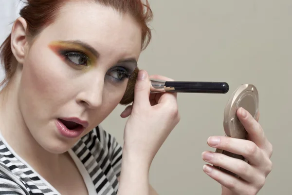 Una mujer aplicando sombra de ojos — Foto de Stock