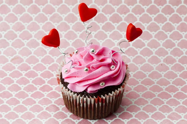 A strawberry cupcake with heart shapes and beads — Stock Photo, Image