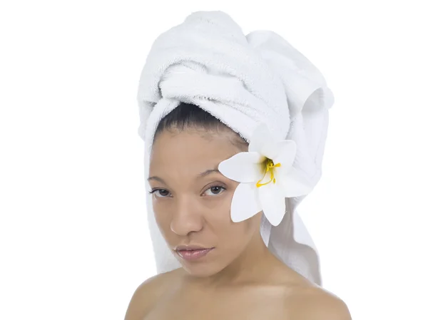 A woman with towel covering her hair and flower behind the ear — Stock Photo, Image