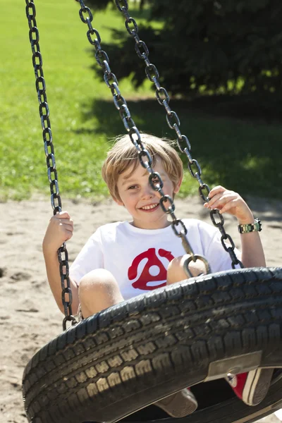 Adorável menino balançando em um pneu swing — Fotografia de Stock