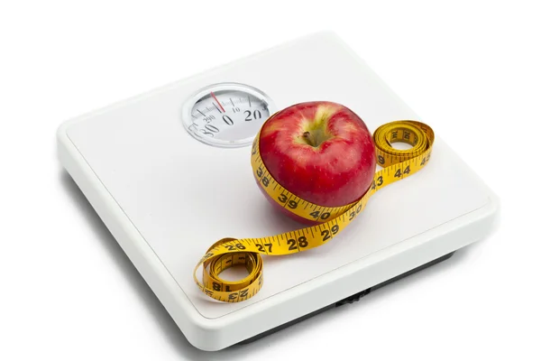 Apple tied with tape measure on weight scale — Stock Photo, Image