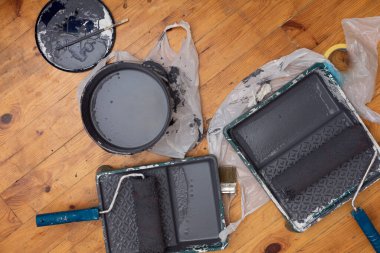 Duvar boyama aletleri tahta zeminde yatıyor..