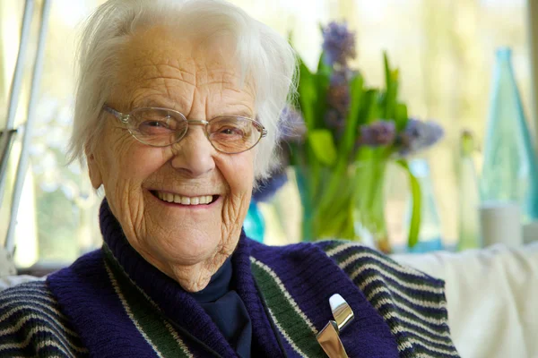 Oudere vrouw kijken naar de camera en glimlachen Stockfoto