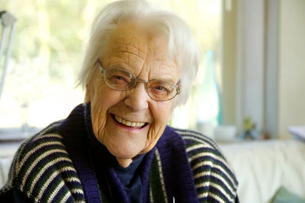 Oudere vrouw kijken naar de camera en glimlachen Stockfoto