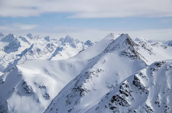 Montanhas nevadas picos nas nuvens céu azul Cáucaso — Fotografia de Stock