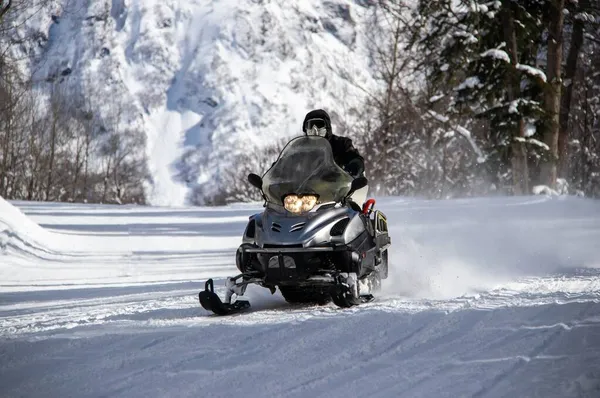 高加索山区雪地的道路上骑着黑色雪地摩托车 免版税图库图片
