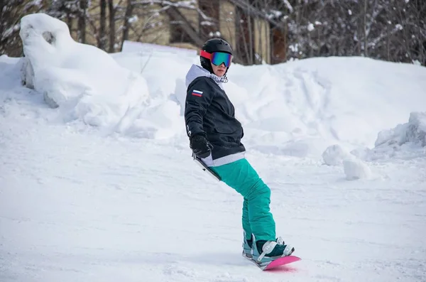 Egy lány a snowboardon leereszkedik a hegy oldalára. — Stock Fotó
