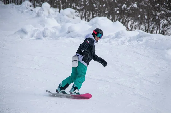 A girl on a snowboard rides down the side of the mountain —  Fotos de Stock