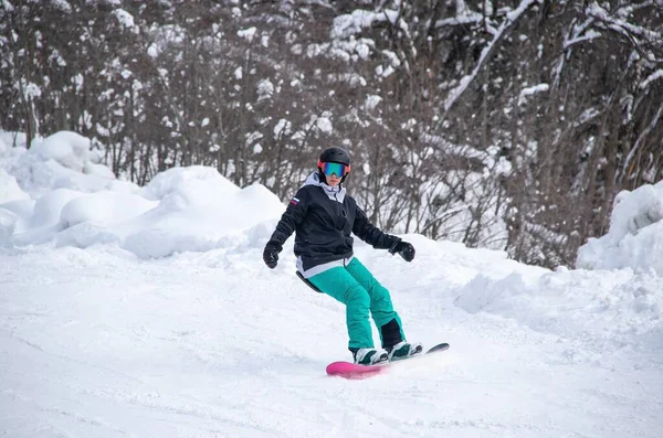 A girl on a snowboard rides down the side of the mountain — Fotografia de Stock