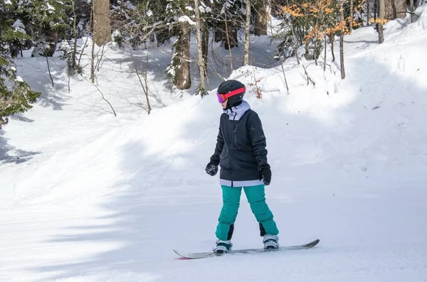 Une fille sur un snowboard descend le flanc de la montagne — Photo