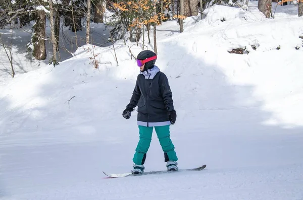 Dziewczyna na snowboardzie zjeżdża z zbocza góry — Zdjęcie stockowe