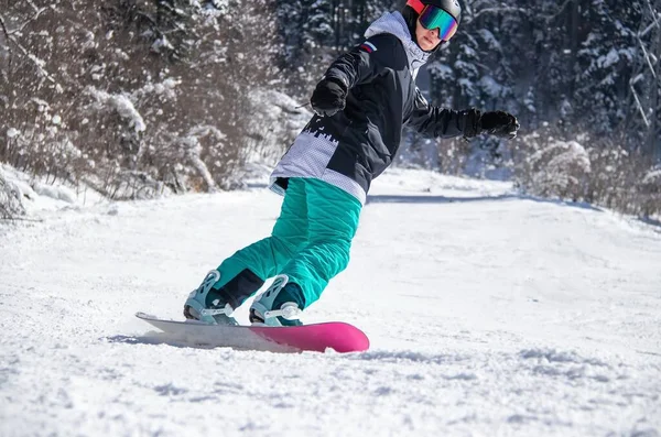 A girl on a snowboard rides down the side of the mountain —  Fotos de Stock