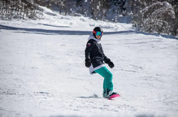 Een meisje op een snowboard rijdt langs de kant van de berg — Stockfoto