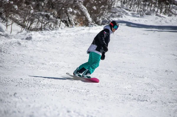 A girl on a snowboard rides down the side of the mountain — Stock Photo, Image