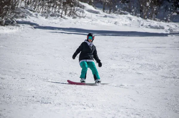 Dziewczyna na snowboardzie zjeżdża z zbocza góry — Zdjęcie stockowe