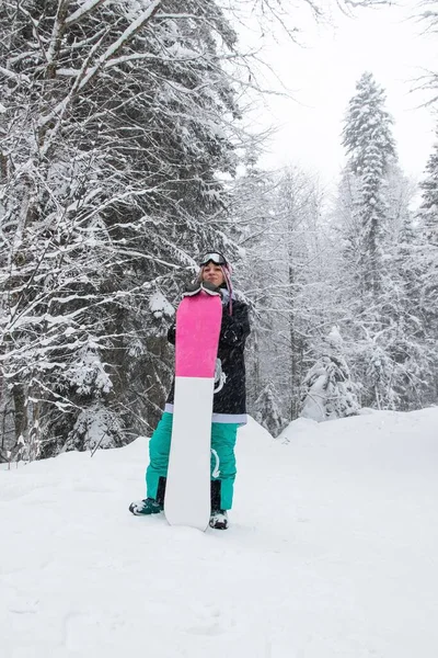 Κορίτσι με μια snowboard στο δάσος στα βουνά και την χιονόπτωση — Φωτογραφία Αρχείου