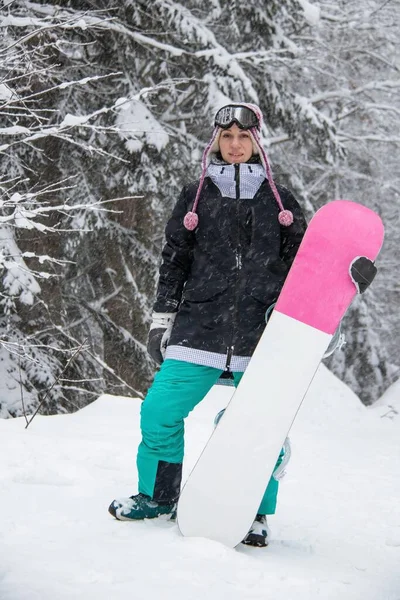 Girl with a snowboard in the forest in the mountains and the snowfall — ストック写真