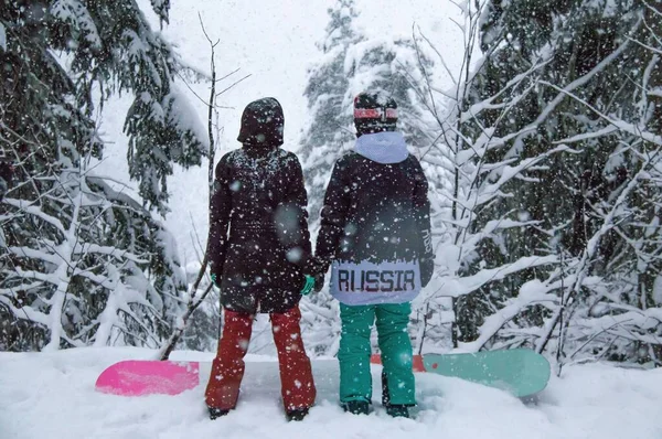 Duas meninas com um snowboards na floresta nas montanhas e a queda de neve — Fotografia de Stock