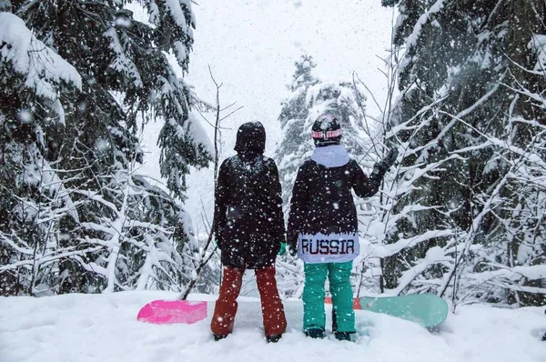 Two girls with a snowboards in the forest in the mountains and the snowfall — Fotografia de Stock