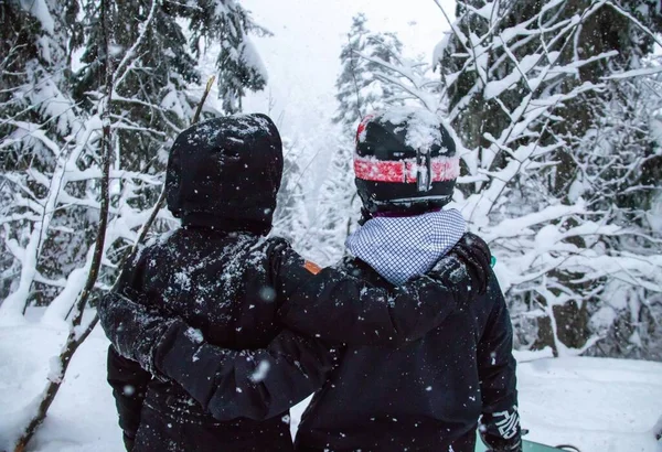 Dağlardaki ormanda snowboard yapan iki kız ve kar yağışı — Stok fotoğraf