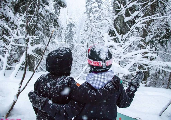 Duas meninas com um snowboards na floresta nas montanhas e a queda de neve — Fotografia de Stock