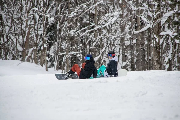 Elinde snowboard olan iki kız dağın yamacında oturuyor. — Stok fotoğraf