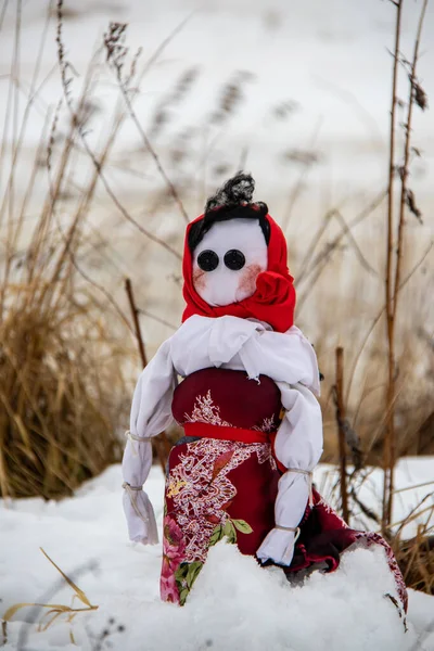 Kurumuş çimenlerde kar üzerinde yanan Maslenitsa bebeği.