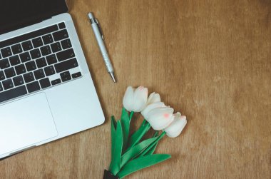 Üst görünüm düz bilgisayar dizüstü bilgisayarı ve çiçek ahşap masada. Boşluğu kopyala
