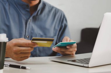 businessman holds a credit card and a calculator at his desk for online shopping.