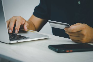 Erkek eli bilgisayar klavyesinde mali ve kredi kartı işlemlerinde ya da İnternet 'te online alışveriş yapıyor..