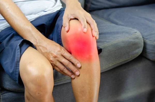 Injury or knee pain of an elderly man on the sofa.