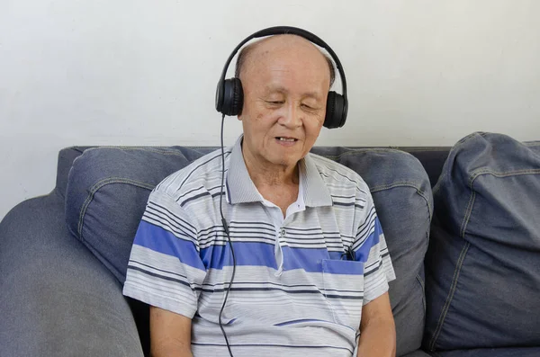 Starszy Mężczyzna Słuchający Muzyki Słuchawkami Sofie — Zdjęcie stockowe