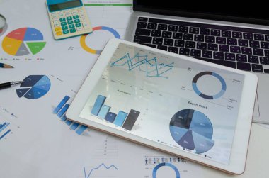 Tablet 'te bilgisayar dizüstü bilgisayarı ve kalemle doküman grafiği ve çizelgesi. İş finans analizi, ofis dijital teknoloji konseptinde pazarlama ve bilgi yatırımı muhasebesi raporunu sunar.
