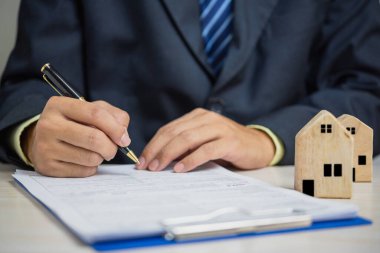 Businessman hand holding pen sign contract document estate load house.Business finance investment insurance and tax concept.