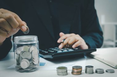 Hand holding money coin saving investment in jar.Business finance accounting economy concept.