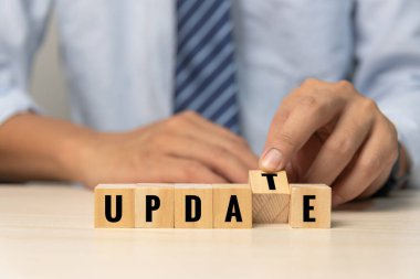 Businessman hand holding wood cube block text update on desk concept.