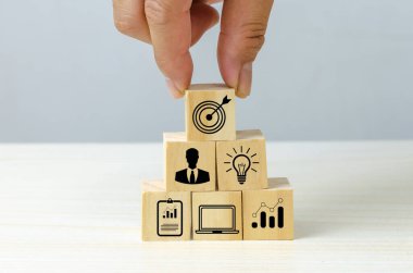 business strategy Action plan Goal and target icons with hand stack a wood cube block on a table. Copy space company development concept.