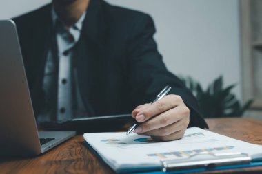 İşadamı elinde kalem tutarak evrak çizelgesi analizi raporları ve şirketteki finansal grafik yatırım pazarlaması masasında..