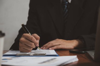 İşadamı masasında kalem imzalı bir belge tutuyor. İş bilgileri sigorta avukatı ve iş konsepti.