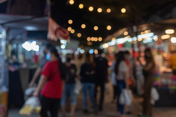 blurred image of night market festival people walking on road with light bokeh for background.