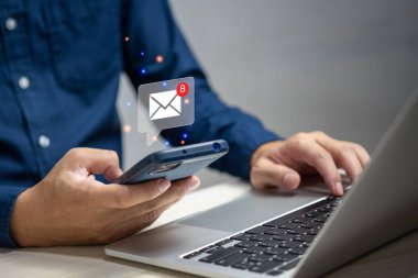 Elde dokunmatik akıllı telefon tutan ve online e-posta simgesini kontrol eden ya da sanal arayüz teknolojisi kavramına sahip İnternet 'teki ortak ve müşterilere e-posta gönderen işadamı.