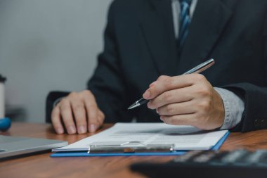 İş adamı elinde kalem çizelgesi tutmakta ve mali grafik yatırım pazarlaması veya vergi sigortasını masasında belgelemektedir..