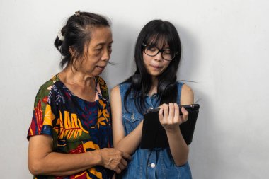 Genç Asyalı kadınlar yaşlı kadınlara modern internet teknolojisi tabletlerini kullanmayı öğretiyor..