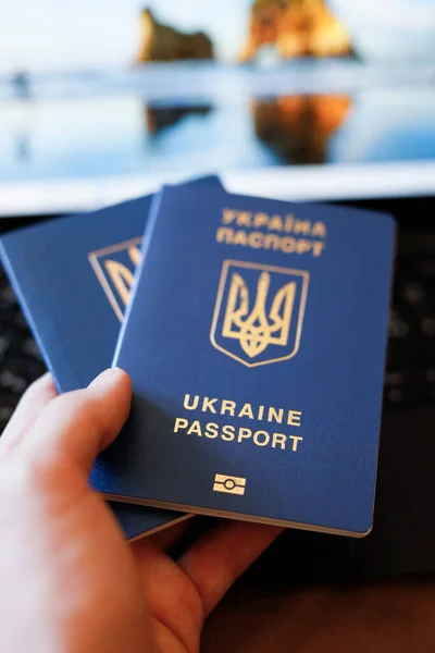 Ukrainian passport in hands in front of a laptop. Book vacation tickets